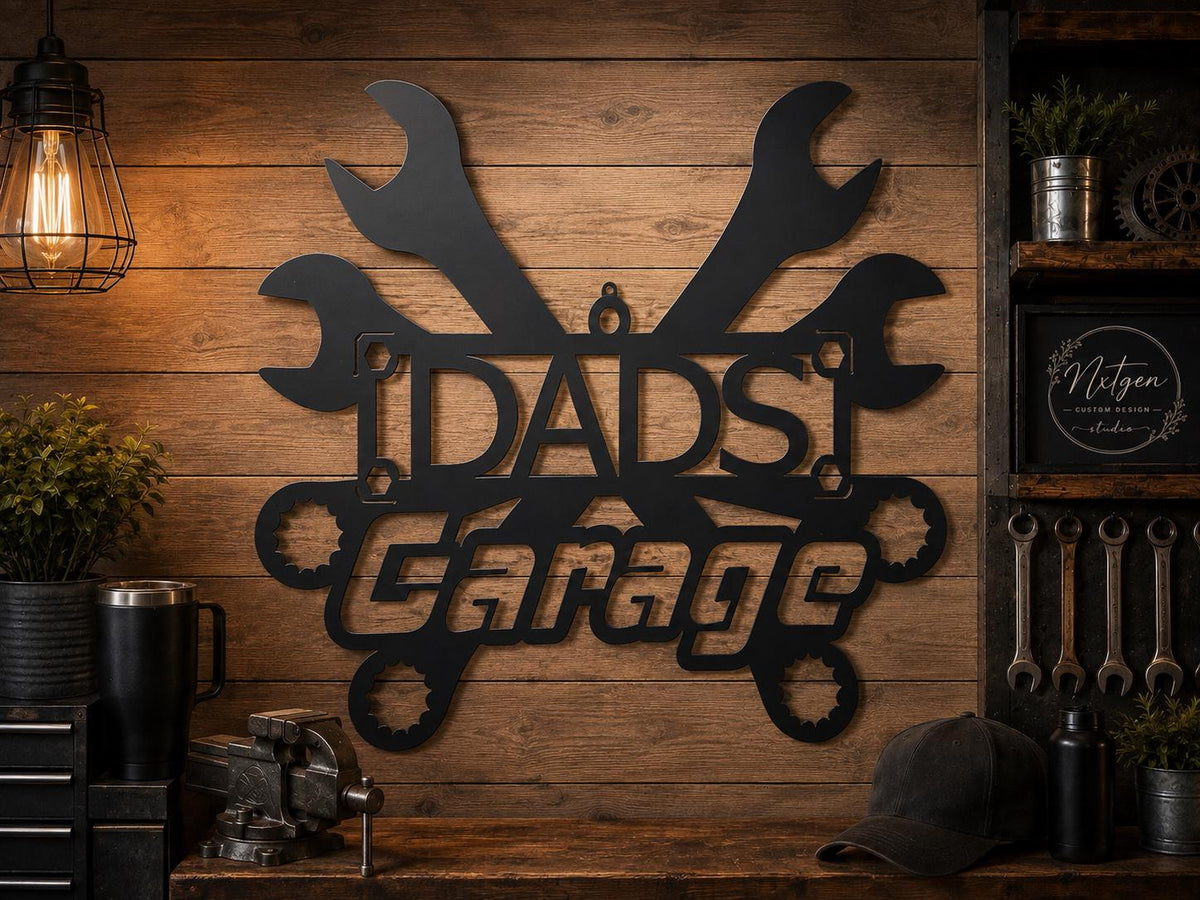 A black metal wall sign reading 'DAD'S Garage' with wrench and gear motifs, mounted on a rustic wood plank wall in a workshop-style room with tools and lighting visible.