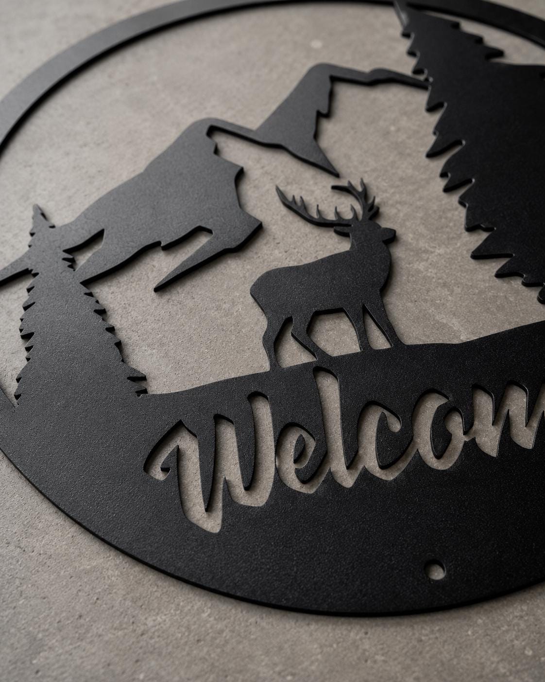 Decorative metal wall art with deer silhouette and 'Welcome' text on a gray background