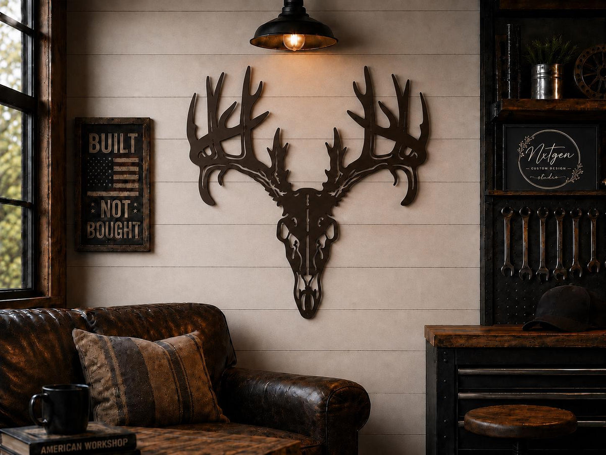 A rustic metal deer skull with large antlers mounted on a beige shiplap wall in a cabin-style room. A brown leather sofa with patterned pillows sits below, and a black pendant light hangs above.